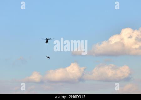 Transporthubschrauber Mi-26 T2B transportiert den Rumpf eines Kampfhubschraubers auf der externen Aufhängung. Schwerer Hubschrauber. Zur Kodifizierung von NAT Stockfoto