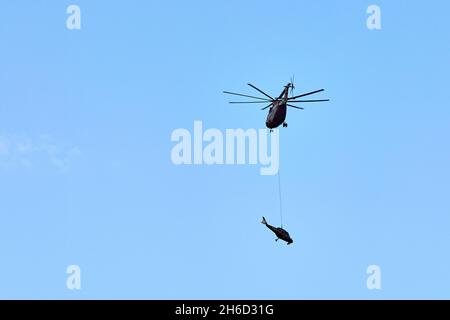 Transporthubschrauber Mi-26 T2B transportiert den Rumpf eines Kampfhubschraubers auf der externen Aufhängung. Schwerer Hubschrauber. Zur Kodifizierung von NAT Stockfoto