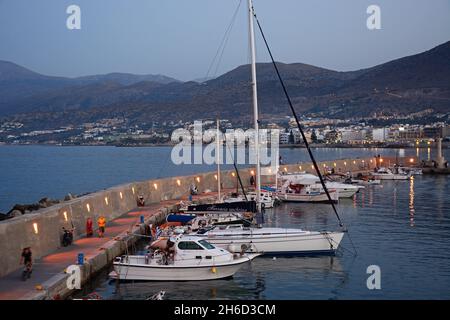 Erhöhten Blick auf Yachten und Boote vertäut im Hafen mit der Stadt nach hinten in der Abenddämmerung, Hersonissos, Kreta, Griechenland, Europa. Stockfoto