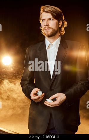 Ein Mann in einem Geschäftsanzug, der in der Nähe des Spieltisches steht. Männlicher Spieler. Leidenschaft, Karten, Chips, Alkohol, Würfel, Glücksspiel, Casino - es ist wie männlich Stockfoto