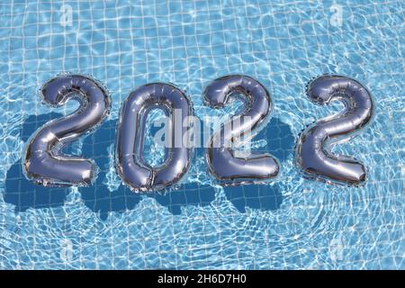 Silberfolienzahlen schweben auf blauem, sauberem Wasser des Schwimmbeckens Stockfoto
