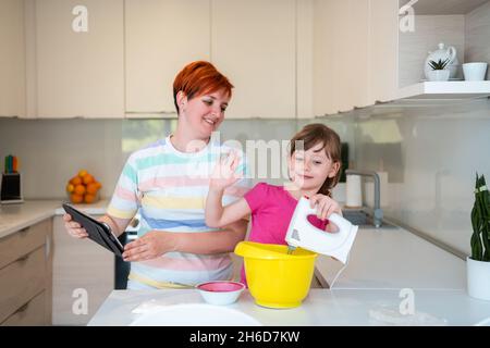 Kleines Mädchen und Mutter machen Tastz Kuchen in kithen Familie Spaß zu Hause Stockfoto