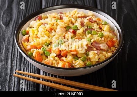 Traditioneller gebratener chinesischer Reis mit Gemüse, Eiern, Garnelen, Schweinefleisch in einer Schüssel auf dem Tisch. Horizontal Stockfoto