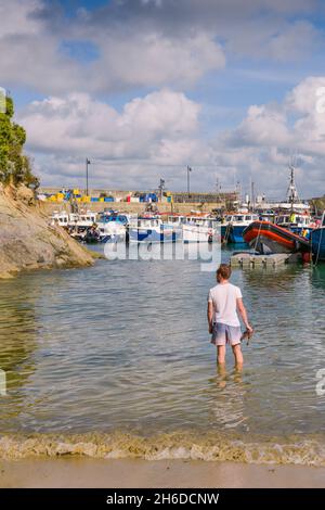 Mann, der im Meer am historisch arbeitenden Newquay Harbour in Newquay in Cornwall steht. Stockfoto