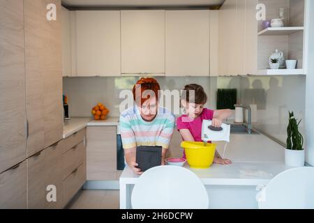 Kleines Mädchen und Mutter machen Tastz Kuchen in kithen Familie Spaß zu Hause Stockfoto