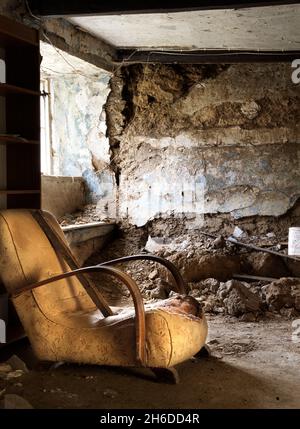Innenansicht des Bauernhauses, zeigt ein Zimmer im Erdgeschoss mit einer eingestürzten Kohlenwand, von Osten, mit einem beschädigten alten Stuhl im Vordergrund, 2018. Stockfoto