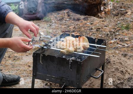 Hühnerfleisch wird auf Spiessen über einem offenen Feuer in der Natur gebraten. Shish Kebab Braten auf Grill Open Air. Stockfoto