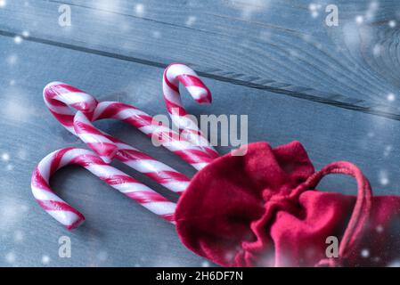 Candy Stöcke in der roten Tasche auf Holz Winter Zeit Hintergrund. Stockfoto