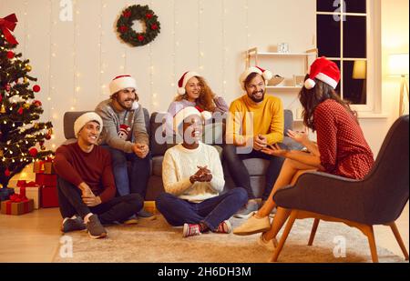 Fröhliche multirassische Freunde kommunizieren miteinander, während sie den Heiligabend genießen. Stockfoto