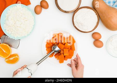 Schritt-für-Schritt-Rezept für Kürbiskuchen Kasserolle in Form eines Zebras, orangefarbener Herbstkuchen mit Orange. Mischzutaten für Kürbiskuchen Draufsicht. Stockfoto