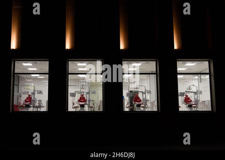 Neue Zahnarztpraxis. Nachtzahnmedizin. Roter Zahnstuhl, Blick durch das Fenster Stockfoto