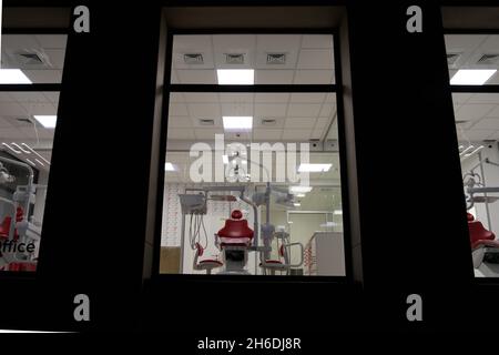 Neue Zahnarztpraxis. Nachtzahnmedizin. Roter Zahnstuhl, Blick durch das Fenster Stockfoto