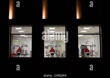 Neue Zahnarztpraxis. Nachtzahnmedizin. Roter Zahnstuhl, Blick durch das Fenster Stockfoto