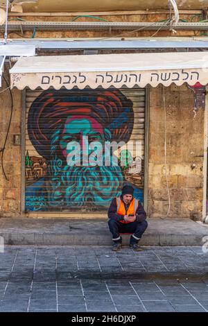 Jerusalem, Israel - 14. Januar: Am 14. Januar 2020 wartet ein Mann auf dem Straßenmarkt in Mahane Yehuda vor einem geschlossenen Geschäft in Jerusalem, Israel Stockfoto