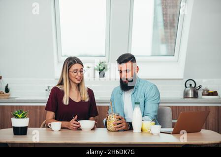 Eine kleine Aufnahme eines jungen Paares, das in der Küche Frühstück macht Stockfoto