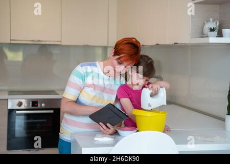 Kleines Mädchen und Mutter machen Tastz Kuchen in kithen Familie Spaß zu Hause Stockfoto