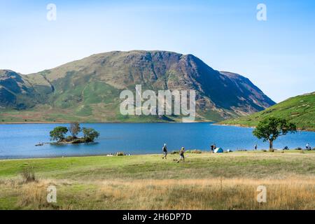 Crummock Water, Blick im Sommer auf ein Wanderpaar, das South Beach auf Crummock Water passiert und in Richtung Mellbreak Fell, Lake District, Cumbria, Großbritannien, blickt Stockfoto