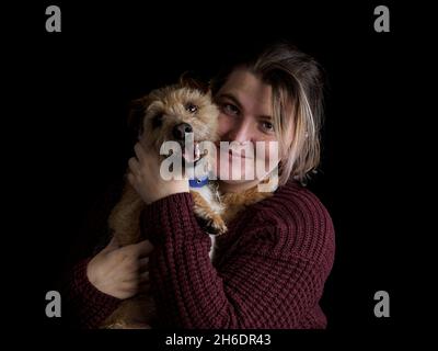Jack Russell mit Drahthaar und Cross Border Terrier wird vom Besitzer für das Portrait, Großbritannien, gekuschelt Stockfoto