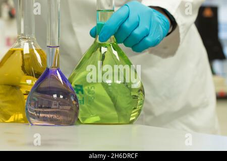 Chemiker im Labor, der Proben in volumetrischen Kolben testet. Bunte Chemieproben Stockfoto