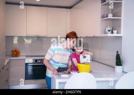 Kleines Mädchen und Mutter machen Tastz Kuchen in kithen Familie Spaß zu Hause Stockfoto