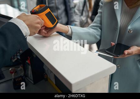 Flughafenmitarbeiter, der die Temperatur des Passagiers mit einem berührungslosen Infrarot-Thermometer misst Stockfoto