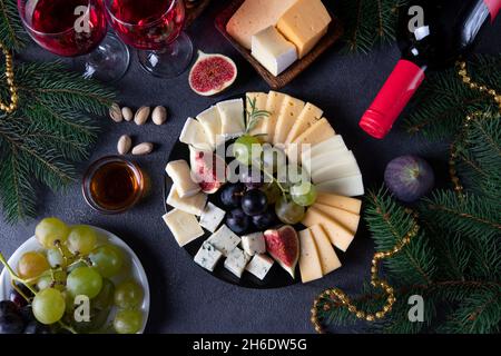 Käse und Obst auf einem runden Teller auf grauem Hintergrund mit zwei Gläsern Wein. Draufsicht Stockfoto