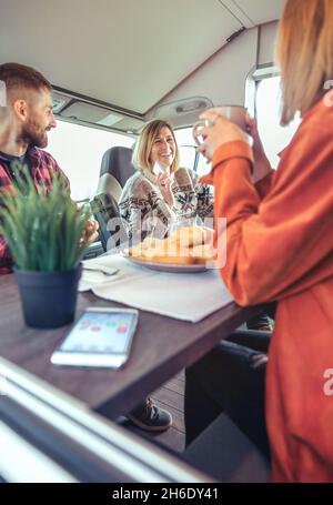 Freunde, die am Morgen in einem Wohnmobil frühstücken Stockfoto