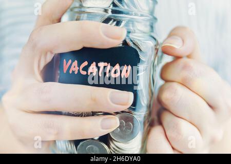 Frau hält Glas mit Münzen für den Urlaub. Flasche mit Ersparnissen für Reisen und Urlaub. Finanzielle Mittel für Unterhaltung und Freizeit auf See. Stockfoto