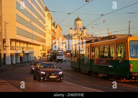 Zwei Straßenbahnen und langsamer Verkehr in Eteläranta, Helsinki, Finnland an einem frühen Wintermorgen. Die Kathedrale von Helsinki im Hintergrund. November 2021. Stockfoto