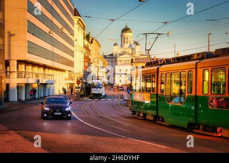 Zwei Straßenbahnen und langsamer Verkehr in Eteläranta, Helsinki, Finnland an einem frühen Wintermorgen. Die Kathedrale von Helsinki im Hintergrund. November 2021. Stockfoto