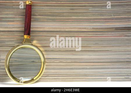 Stapel von Zeitschriften und Lupe auf weißem Hintergrund.Konzept des Lernens und der Verfolgung von Wissen Stockfoto