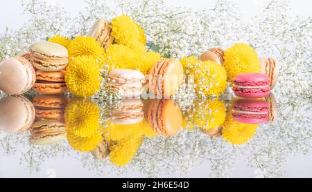 Bunte Macarons und schöne Blumenkomposition auf weißem Feiertagshintergrund. Hochwertige Fotos Stockfoto