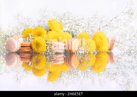 Bunte Macarons und schöne Blumenkomposition auf weißem Feiertagshintergrund. Hochwertige Fotos Stockfoto