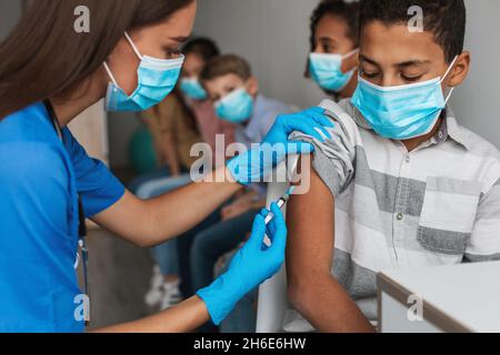 Medizinischer Arbeiter, Der Impfstoff Macht Injektion, Der Afroamerikanische Junge Im Innen-Bereich Impft Stockfoto