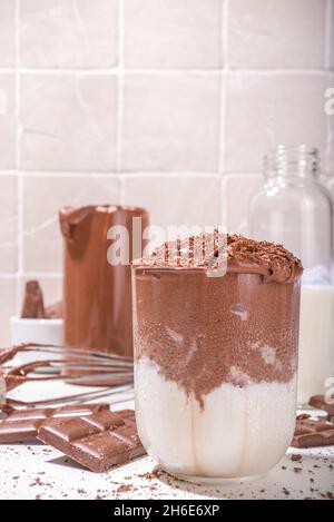 Heiße Schokolade im Stil eines ausgepeitschten Dalgona-Kaffees, moderner Kakao-cremiger Drink mit Schokoladenscheiben auf dem Küchentisch, Platz zum Kopieren Stockfoto
