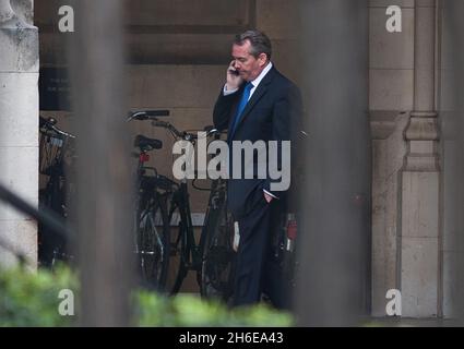 Verteidigungsminister Liam Fox plaudert auf seinem Handy, als er das Unterhaus verlässt, nachdem er Fragen über seine Freundschaft mit Adam Werrity beantwortet hat. Stockfoto