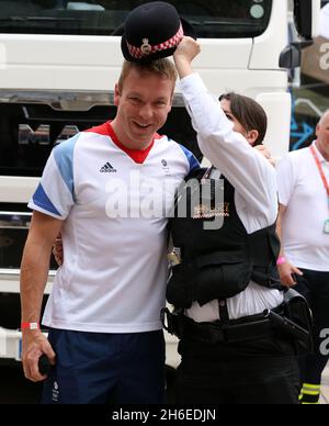 Der Olympiasieger Chris Hoy genießt einen Witz mit einer Polizistin während der Parade der Olympischen und Paralympischen Spiele in Großbritannien. Stockfoto