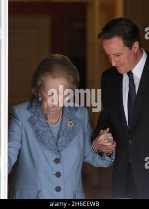 Baroness Margaret Thatcher hält sich an Premierminister David Cameron, als sie nach einem Besuch in der Downing Street heute Nachmittag die Nummer 10 verlässt. Stockfoto