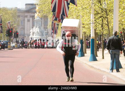 Charity-Läufer Tony Phoenix-Morrison, bekannt als Tony the Fridge on the Mall, als er die London Marathons hinter sich führt, während er einen Kühlschrank trägt. Stockfoto