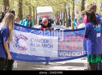 Charity-Läufer Tony Phoenix-Morrison, bekannt als Tony the Fridge on the Mall, als er die London Marathons hinter sich führt, während er einen Kühlschrank trägt. Stockfoto