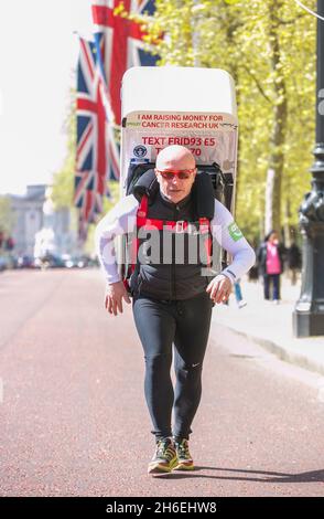 Charity-Läufer Tony Phoenix-Morrison, bekannt als Tony the Fridge on the Mall, als er die London Marathons hinter sich führt, während er einen Kühlschrank trägt. Stockfoto