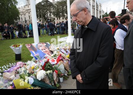 Justin Welby, der Erzbischof von Canterbury, ist mit einem Bild von Ehrungen zu sehen, die für den ermordeten Abgeordneten Jo Cox in Westminster hinterlassen wurden Stockfoto