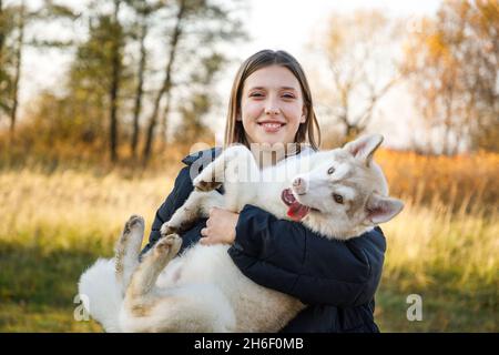 Junges Mädchen mit Husky Welpen im Herbstwald Stockfoto