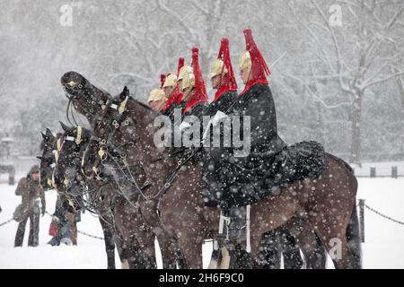 Wachen zu Pferd im Schnee bei der Parade der Pferdewächter im Zentrum von London. Stockfoto