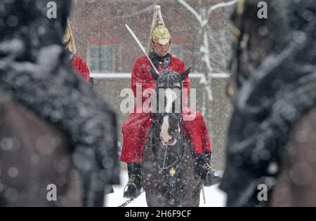 Wachen zu Pferd im Schnee bei der Parade der Pferdewächter im Zentrum von London. Stockfoto