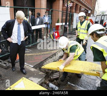 Boris Johnson, der Bürgermeister von London, sieht zu, wie Arbeiter eine Decke über offenen Straßenarbeiten am Chandos Place, Covent Garden, London, legen. Der Bürgermeister von London, Boris Johnson, hat heute einen Verhaltenskodex eingeführt, der darauf abzielt, die Verzögerungen und Staus durch Straßenbauarbeiten in London zu verringern. Stockfoto