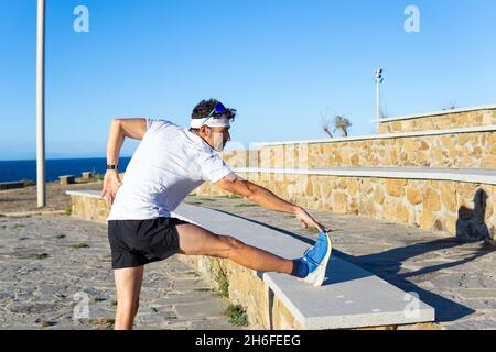 Seitenansicht eines jungen kaukasischen Mannes, der auf der Parkstretche trainiert Stockfoto
