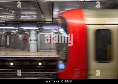 U-Bahn-Station Westminster, London, Großbritannien, mit einer fahrenden U-Bahn, die in den Bahnsteig fährt. Logo Stockfoto