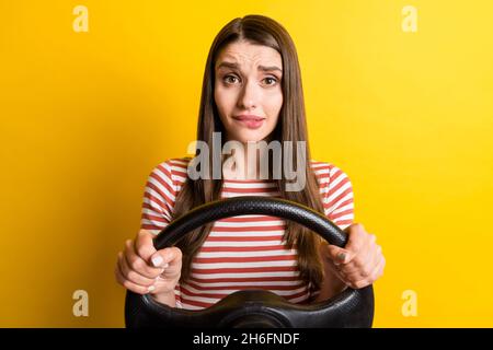 Portrait von attraktiven verwirrt Mädchen halten Lenkrad fahren beißende Lippe beunruhigend isoliert über helle gelbe Farbe Hintergrund Stockfoto