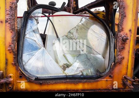Nahaufnahme einer gelben rostigen alten zerhackelten Traktortür mit einer zerbrochenen Fensterscheibe, aufgenommen am Dungeness Beach in Kent, Großbritannien, 14th. November 2021 Stockfoto